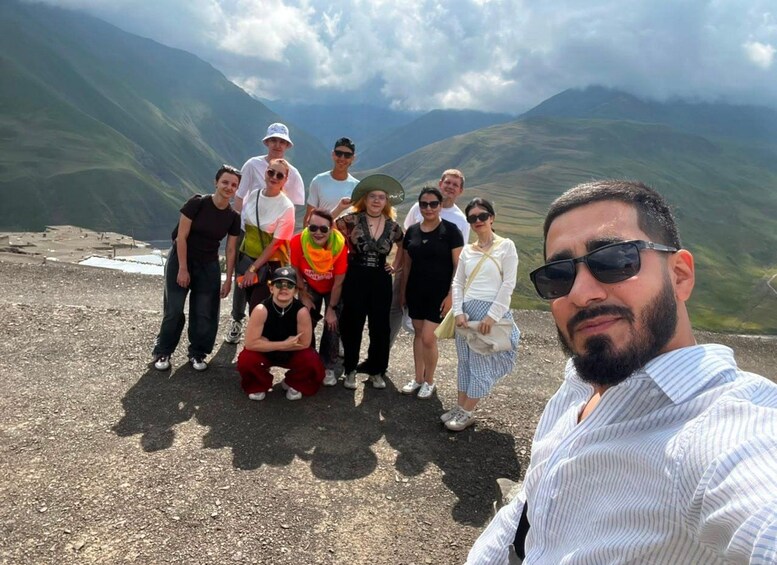 A group of people standing on a mountain ridge with a vast landscape in the background. 2