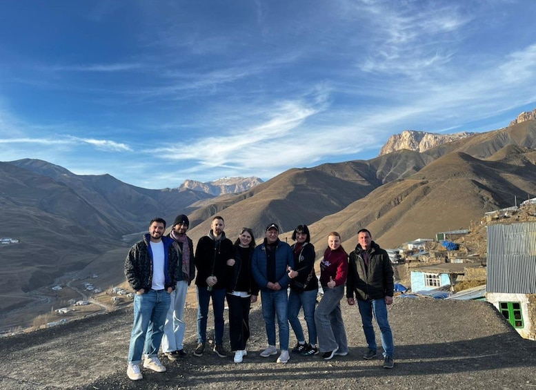 A group of people standing on a mountain ridge with a valley and mountains in the background. 4