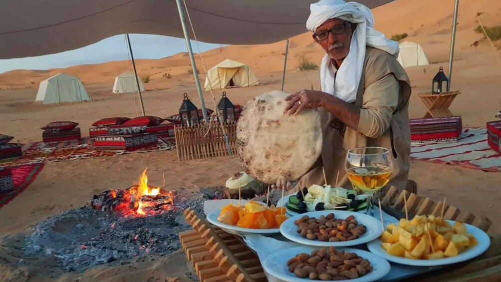 Cacampamento en el desierto con tiendas de campaña, fuego y una mesa con comida y bebida. 5