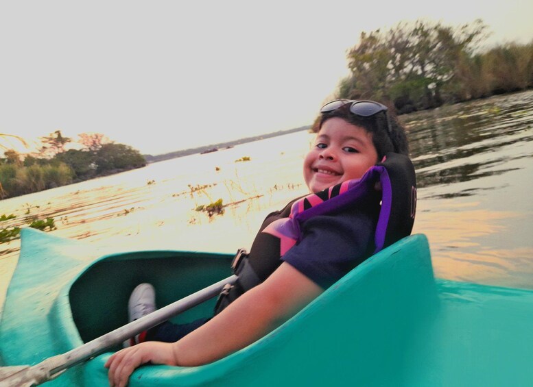Una persona en kayak verde sobre un cuerpo de agua, con árboles y una orilla distante. 4