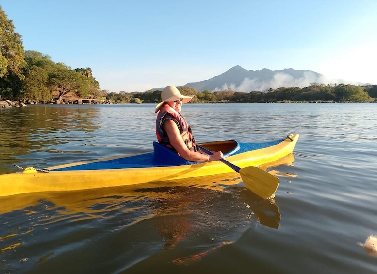 Una persona practica kayak en un lago tranquilo, con una montaña al fondo. 5