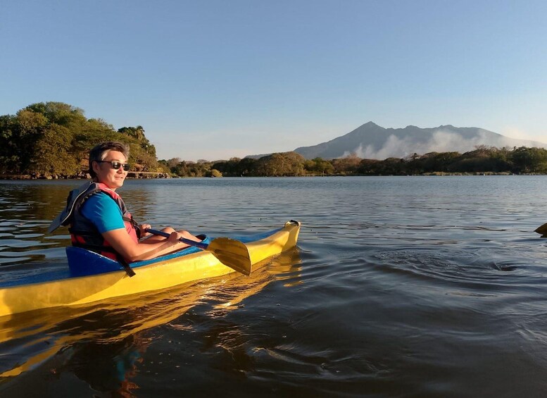 Una persona en kayak sobre aguas tranquilas, con una montaña al fondo. 1