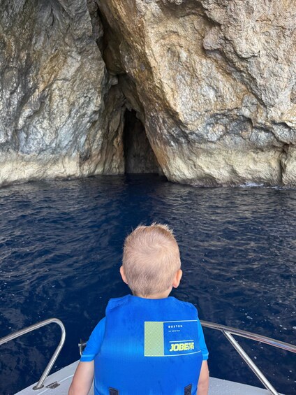 Una persona en un bote, con una camisa azul, mirando la entrada de una cueva rocosa en el agua. 4
