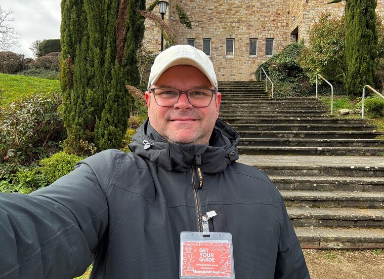 A person taking a selfie with a stone building and steps in the background. 5