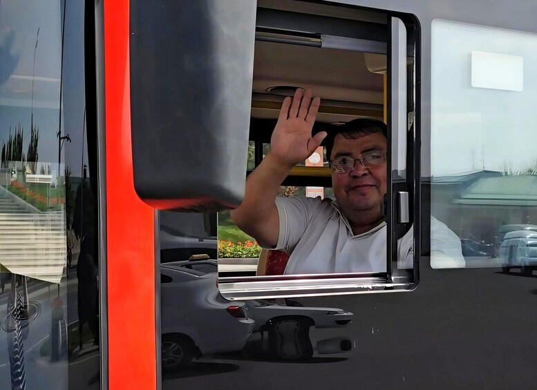 A person waving from inside a vehicle with a red and black exterior. 4