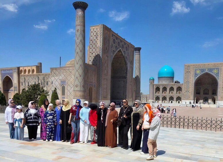A group of people standing in front of a historic building with intricate architecture and a large blue dome. 3