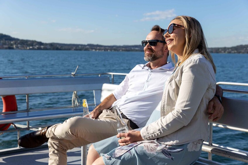 A couple sitting on a boat with a body of water and a distant shoreline in the background. 3