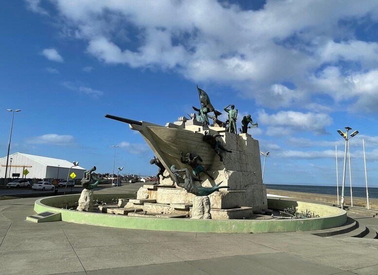 Escultura con temática marina que muestra figuras a bordo de un barco, ubicada en una plaza pública bajo un cielo despejado. 3