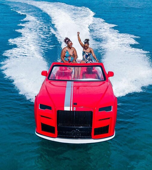Une voiture de sport rouge roule sur une eau d’un bleu cristallin, laissant derrière elle une vague. 4