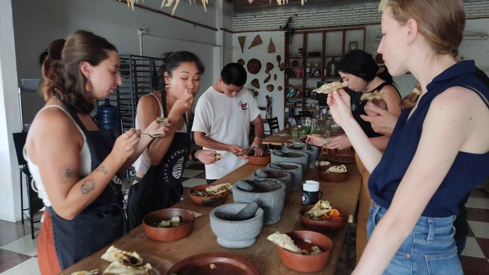 A group of people preparing food in a kitchen with stone bowls and a mortar. 4