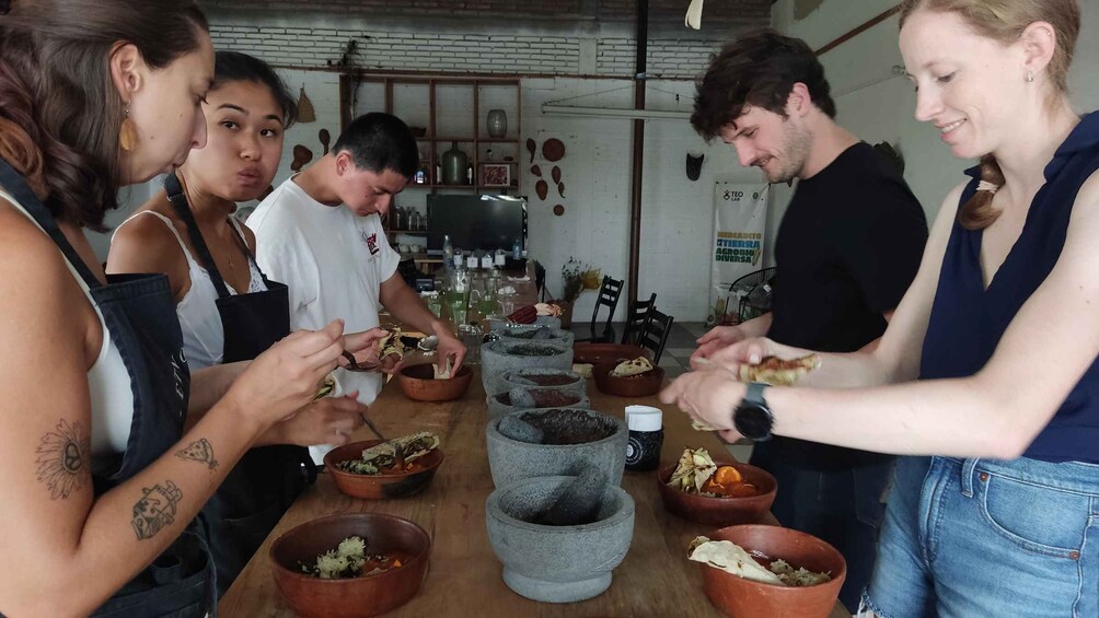 A group of people preparing food with various bowls and cooking utensils on a table. 3