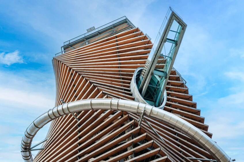 A modern architectural building with a unique angular design, featuring a prominent spiral staircase and a glass elevator. 2