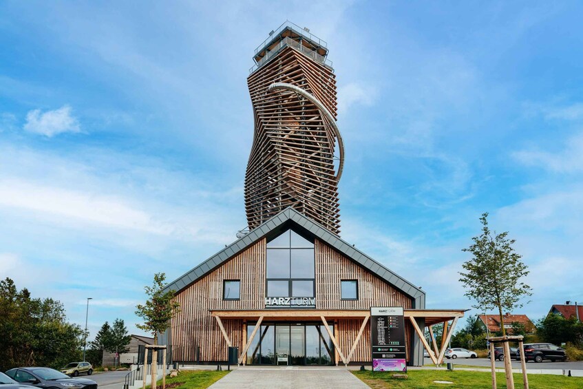 A modern building with a unique twisted tower structure and a wooden facade. 1