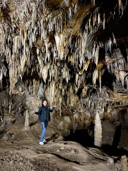 A person standing in a cave with stalactites hanging from the ceiling. 2