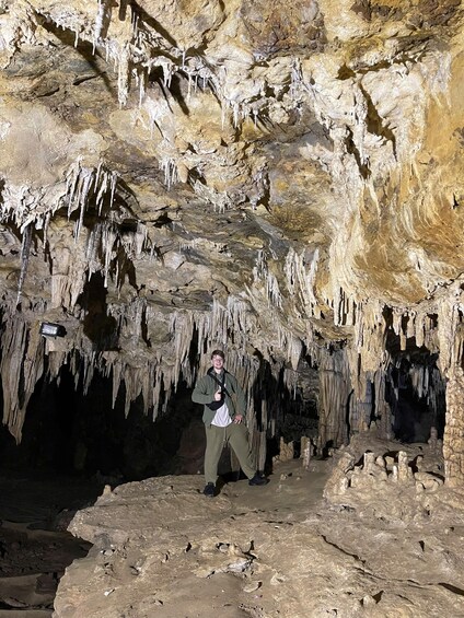 A person standing in a cave with stalactites hanging from the ceiling. 3