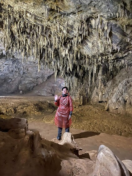 A person standing in a cave with stalactites hanging from the ceiling. 5