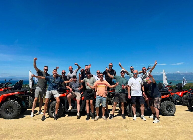 Un grupo de personas posando frente a vehículos todo terreno bajo un cielo azul despejado y montañas lejanas. 3