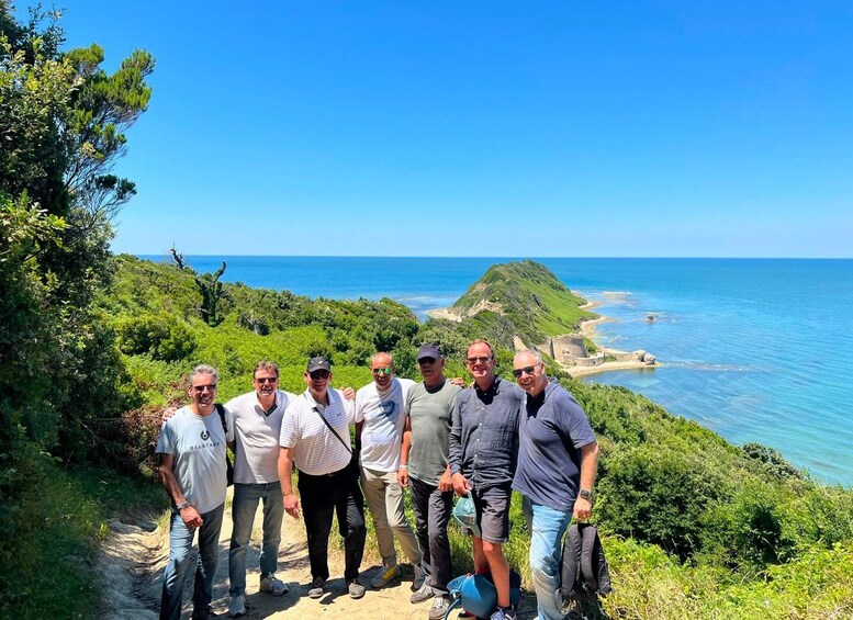Un grupo de personas sobre un sendero de tierra contemplando un paisaje costero con cielo azul despejado. 4