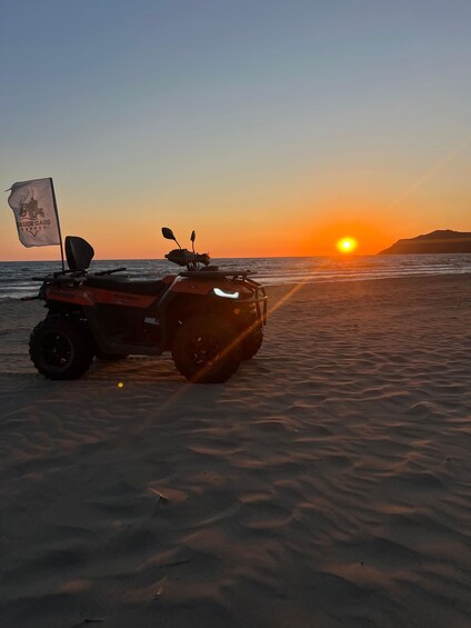 Cuadriciclo estacionado en una playa arenosa con un atardecer de fondo. 2