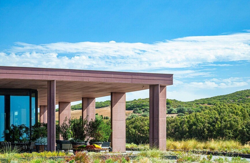 A modern building with a concrete structure, surrounded by greenery and hills in the background. 3