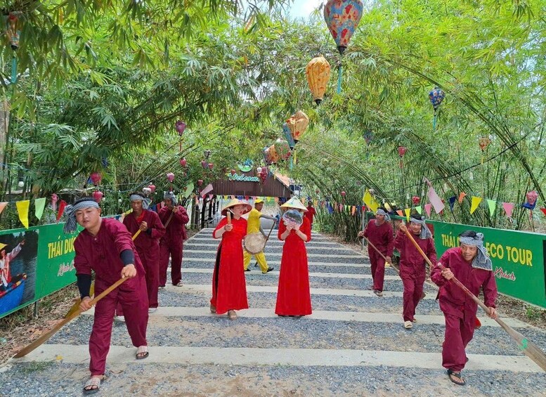 A procession with participants in traditional attire, carrying musical instruments, and walking along a pathway lined with bamboo trees and colorful decorations. 3
