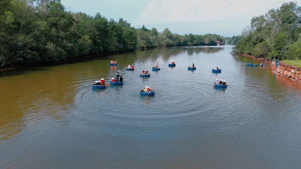A river with several small boats carrying people, surrounded by dense greenery. 5