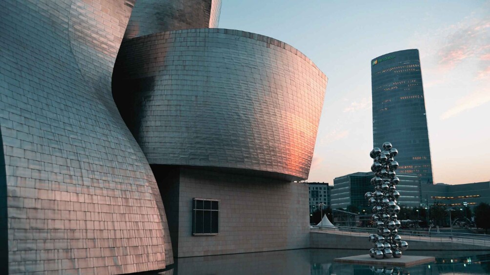 A modern architectural structure with a metallic facade and a reflective sculpture. 5