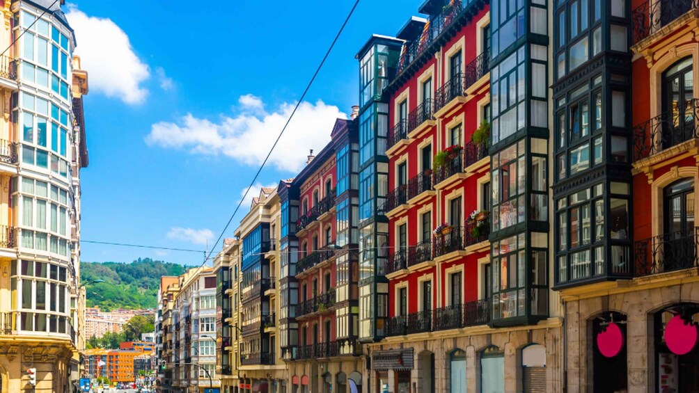 A street lined with colorful buildings, a clear blue sky, and a distant green hill. 4