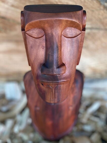 A wooden sculpture with a carved face, set against a blurred background. 3