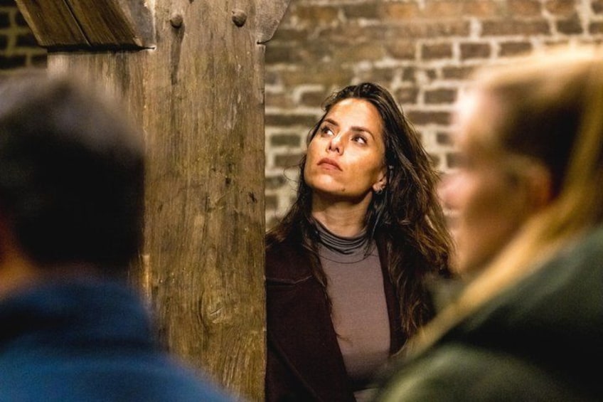A person standing in a wooden structure with a brick wall in the background. 5