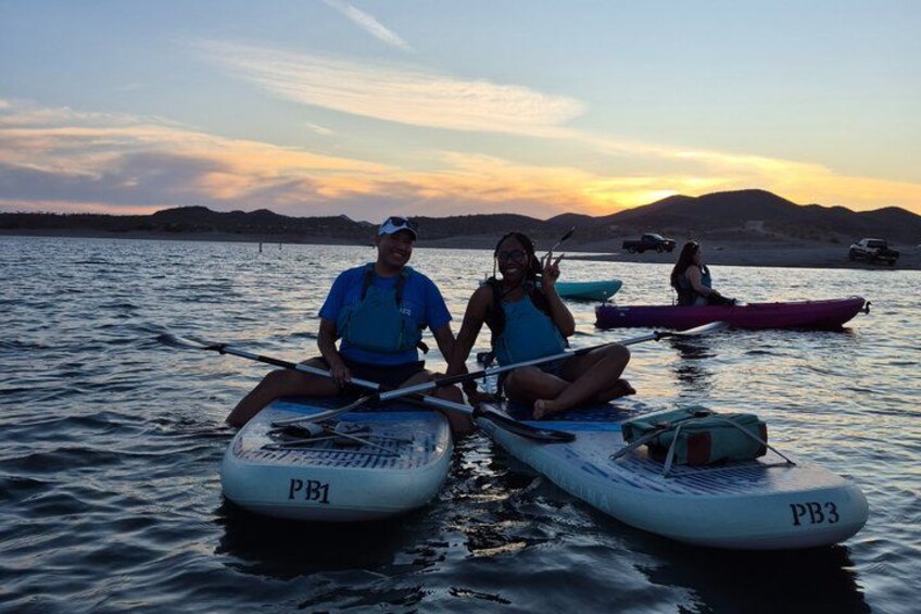 Two people kayaking on a calm lake with a sunset in the background. 5