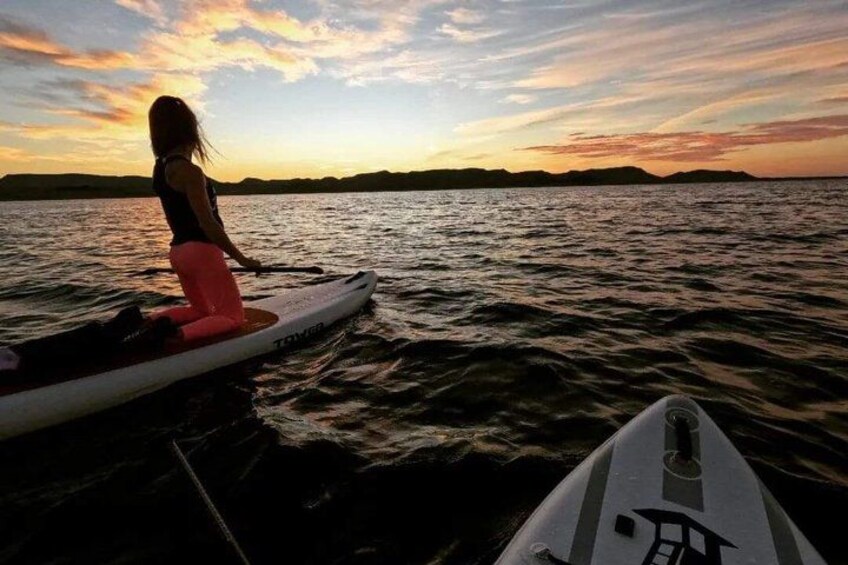 A person on a paddleboard in a body of water during sunset. 3