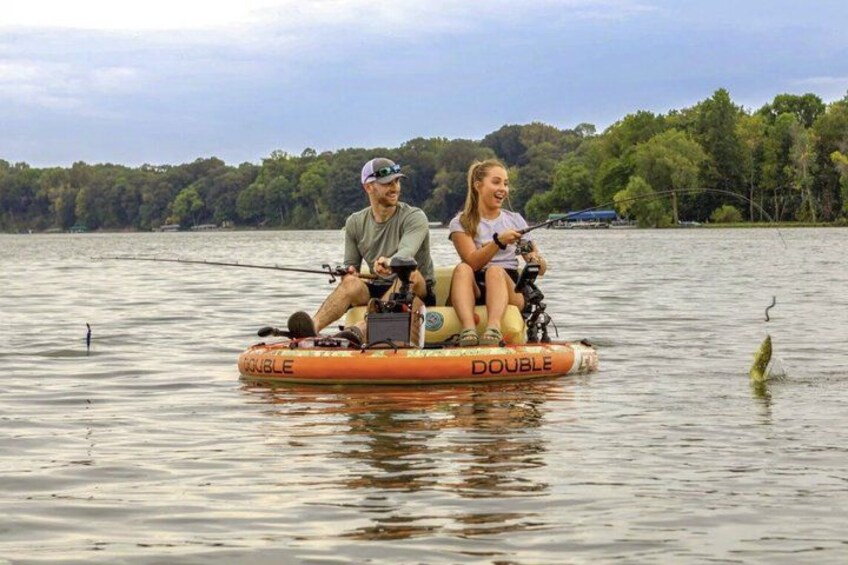 A man and a woman on a small inflatable boat on a lake with trees in the background. 2