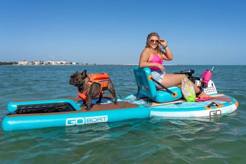 A person and a dog on a blue inflatable boat with a life jacket on the dog. 1