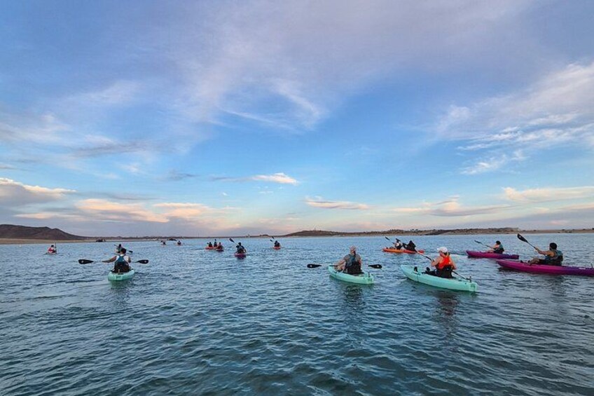 People kayaking on a calm body of water with a clear sky. 2