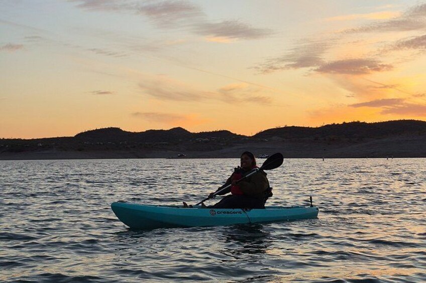 A person kayaking on a body of water during sunset. 5