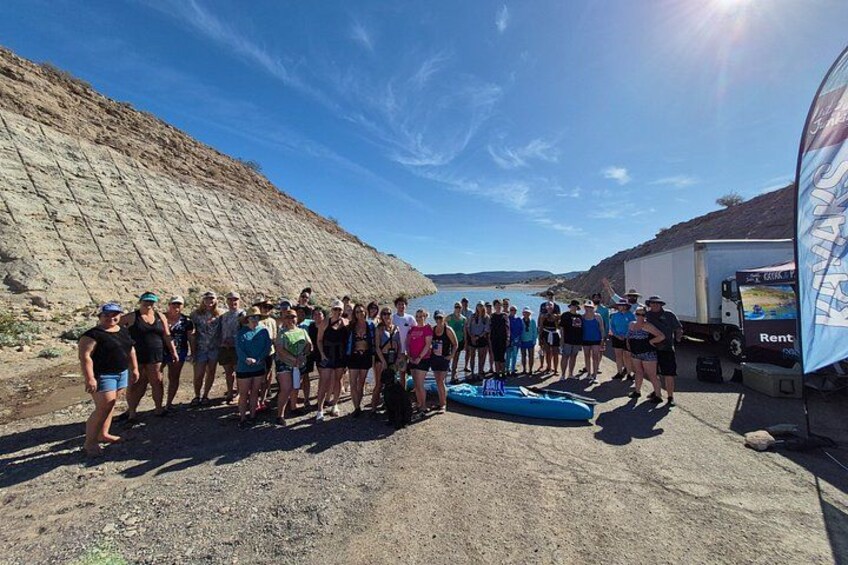 A group of people standing on a dirt path with a rocky hillside and a truck parked nearby. 4