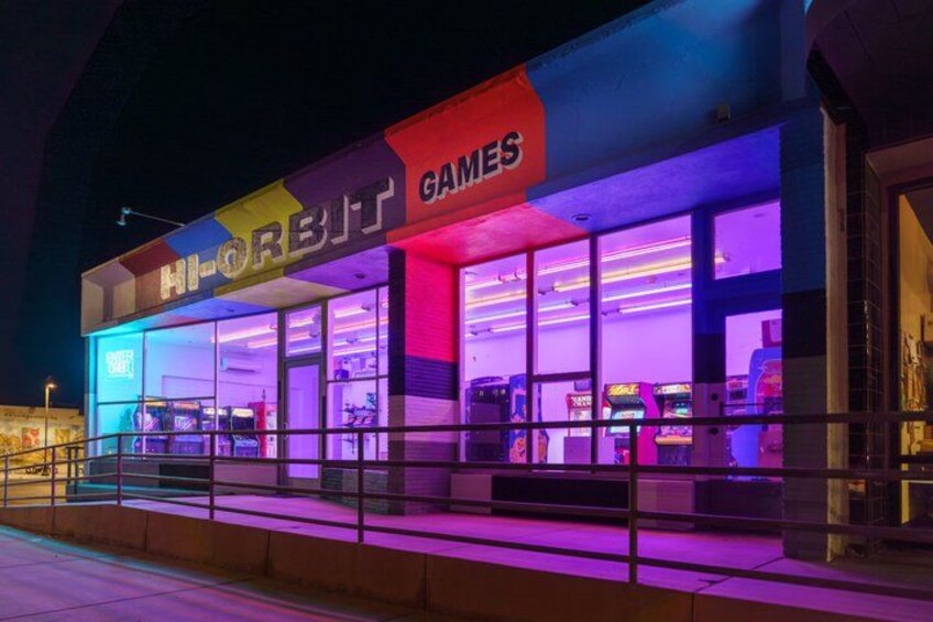 A brightly lit arcade with neon signs and various gaming machines. 1