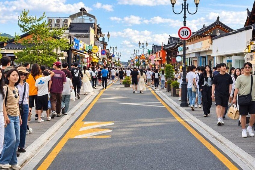 A crowded street lined with traditional buildings, a speed limit sign, and pedestrians. 4