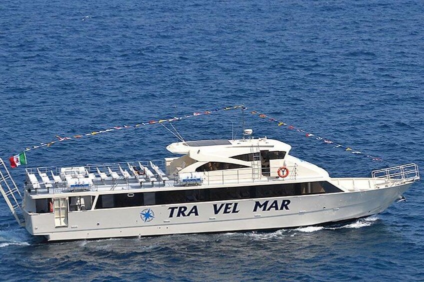 A white boat with 'TRA VEL MAR' written on its side, sailing on blue water. 1