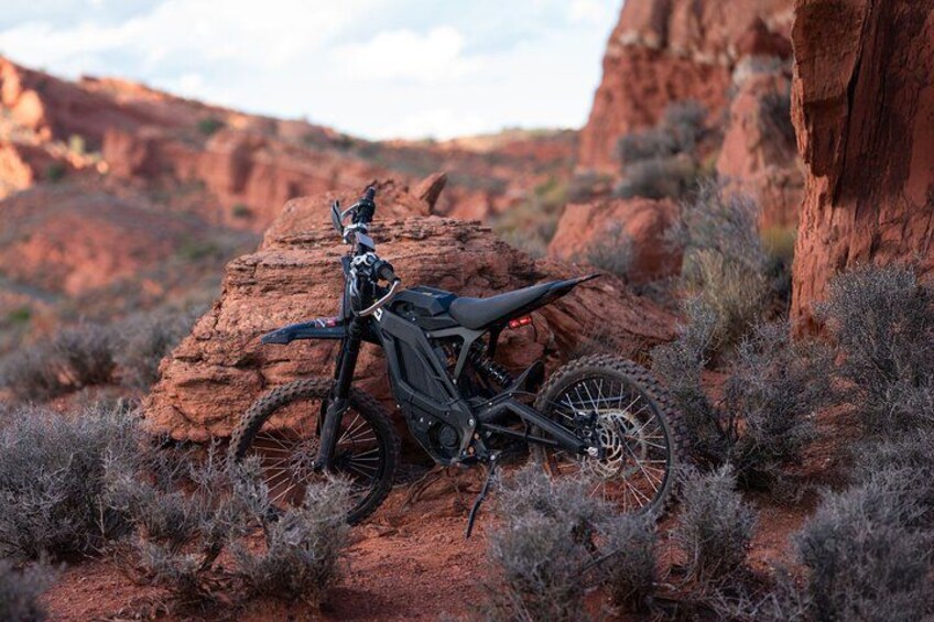 A dirt bike parked on a rocky terrain with sparse vegetation. 5
