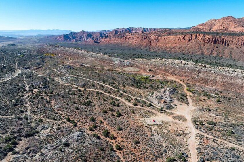 A rugged desert landscape with winding roads and distant mountains. 4