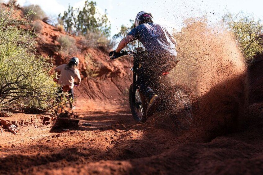 A person riding a dirt bike on a dirt path, kicking up dust. 3