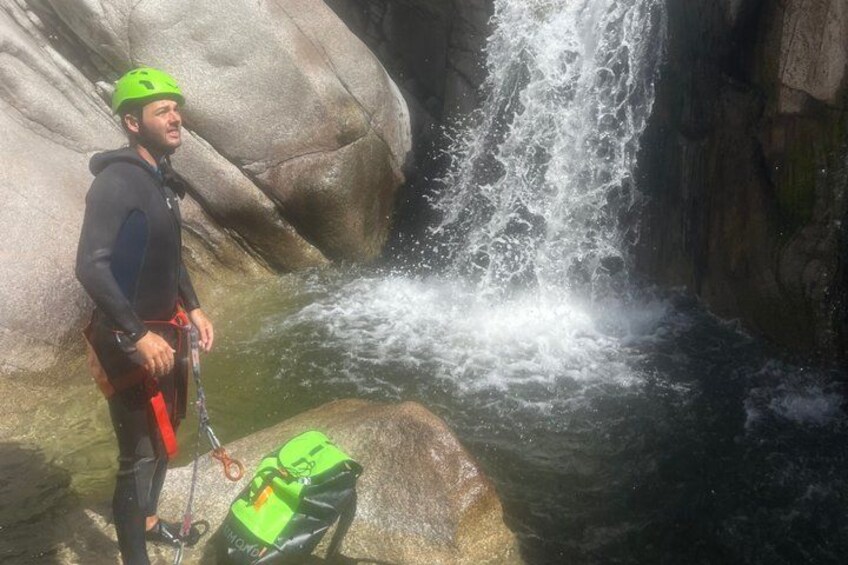 A person in a wetsuit and helmet near a waterfall. 2