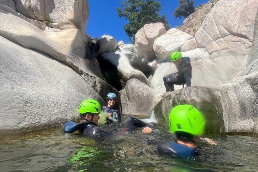 People in water with helmets, navigating through a rocky terrain. 3