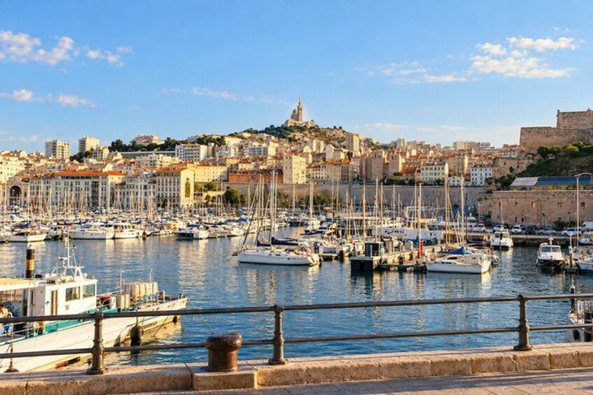 A harbor with boats, a cityscape, and a hill with a castle-like structure. 2