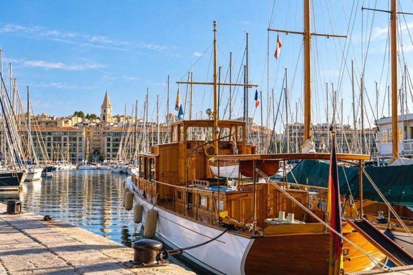 A marina with multiple sailboats docked, a wooden boat in the foreground, and buildings in the background. 4