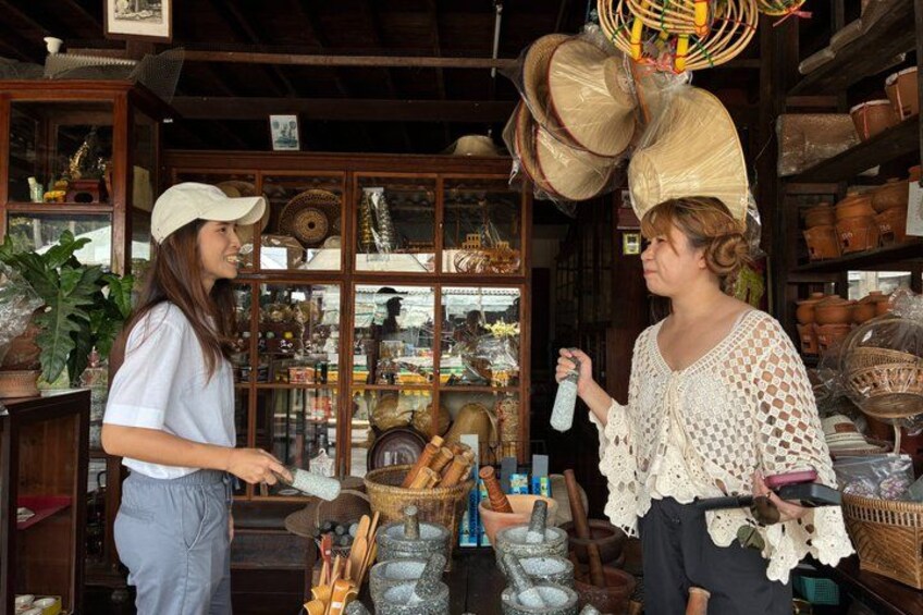 Two people in a store with shelves of baskets, pottery, and other items. 3