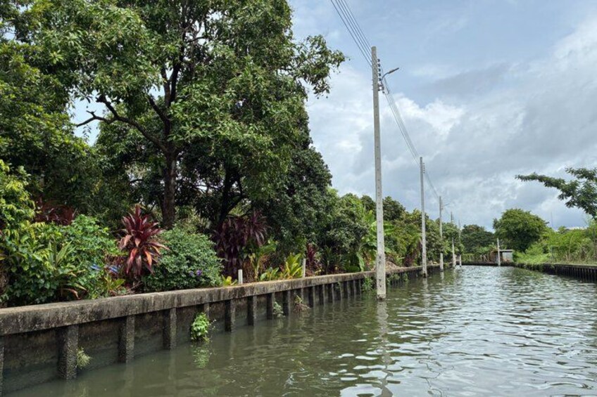 A canal with a concrete embankment, surrounded by lush greenery and trees. 4