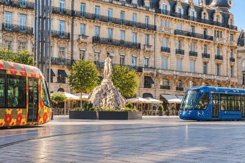 A city square with a statue, tram lines, and a historic building. 5